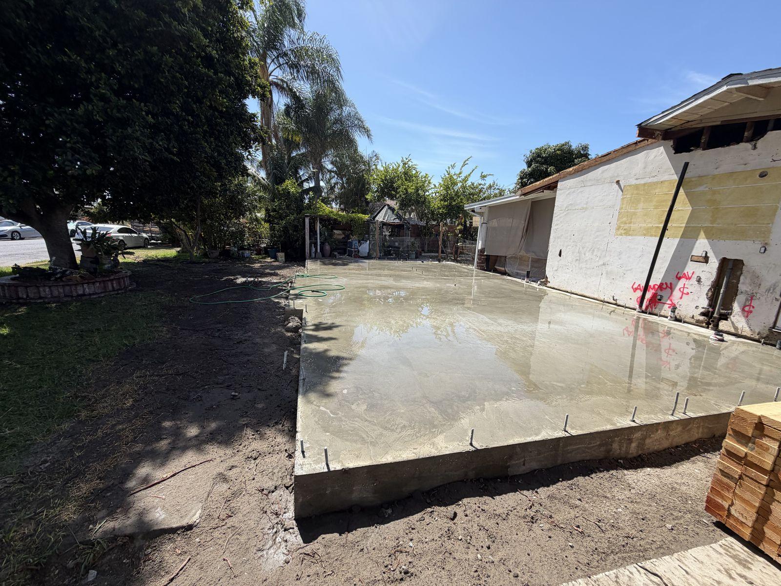 Freshly poured concrete slab foundation for an ADU next to the main house