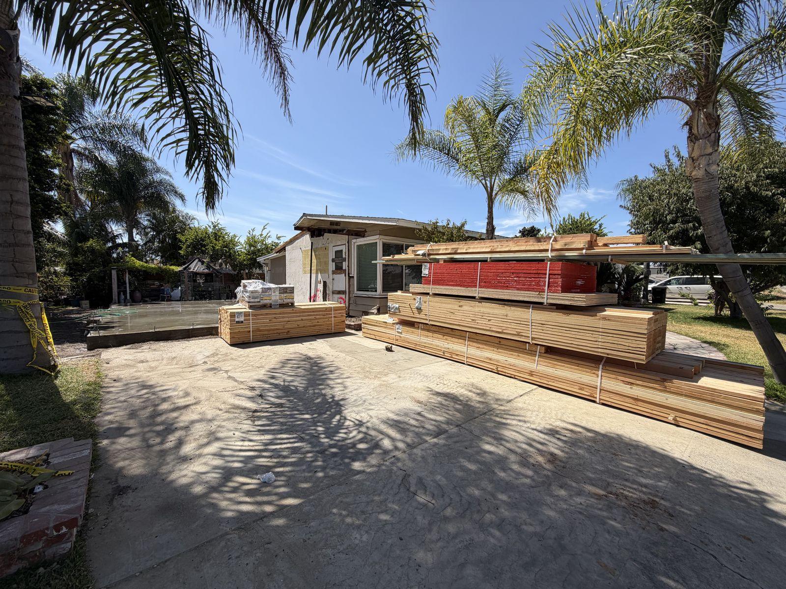 Framing lumber and material delivery staged in the driveway for an ADU build