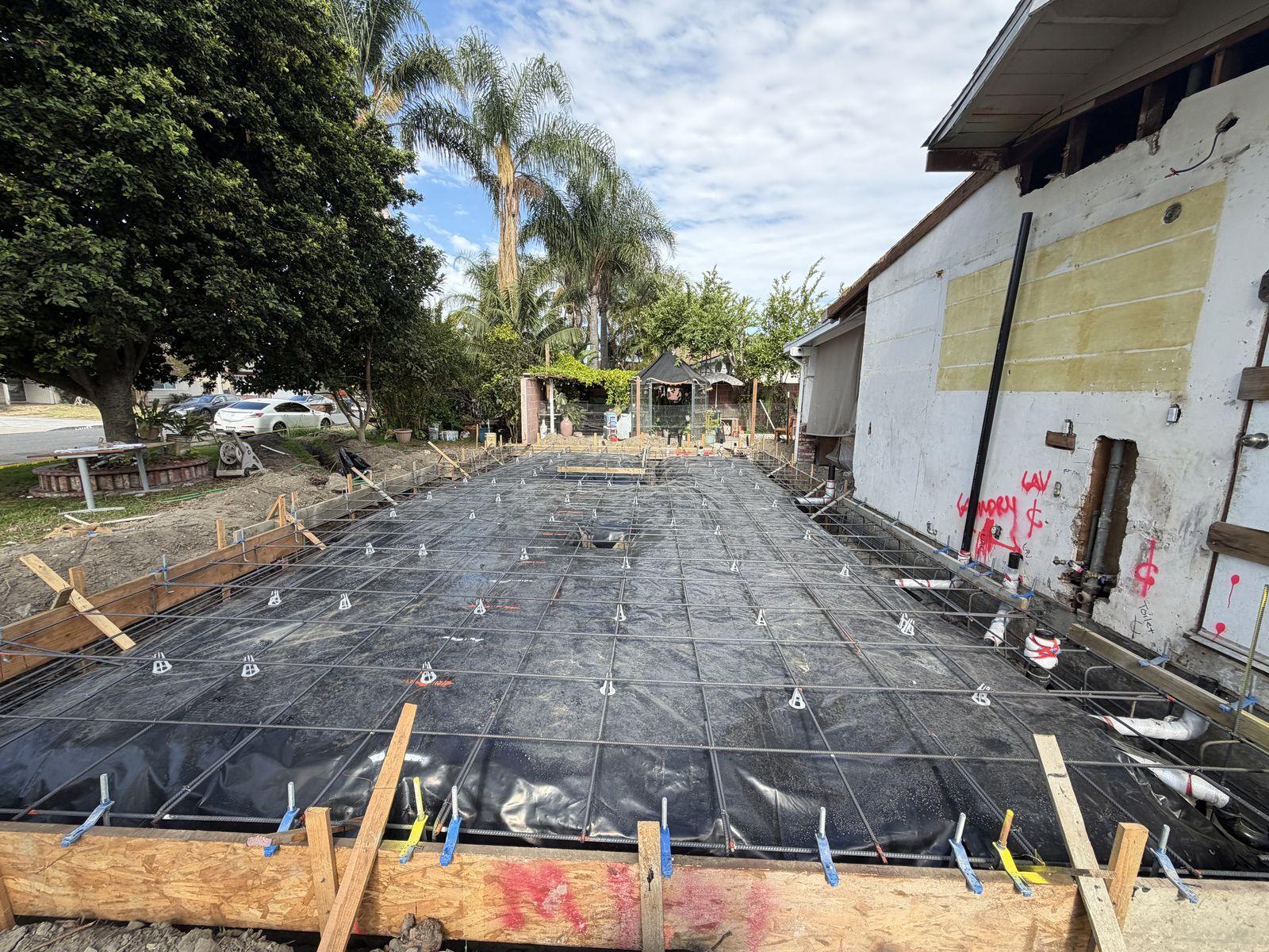 Rebar grid and vapor barrier laid out ahead of an ADU foundation pour