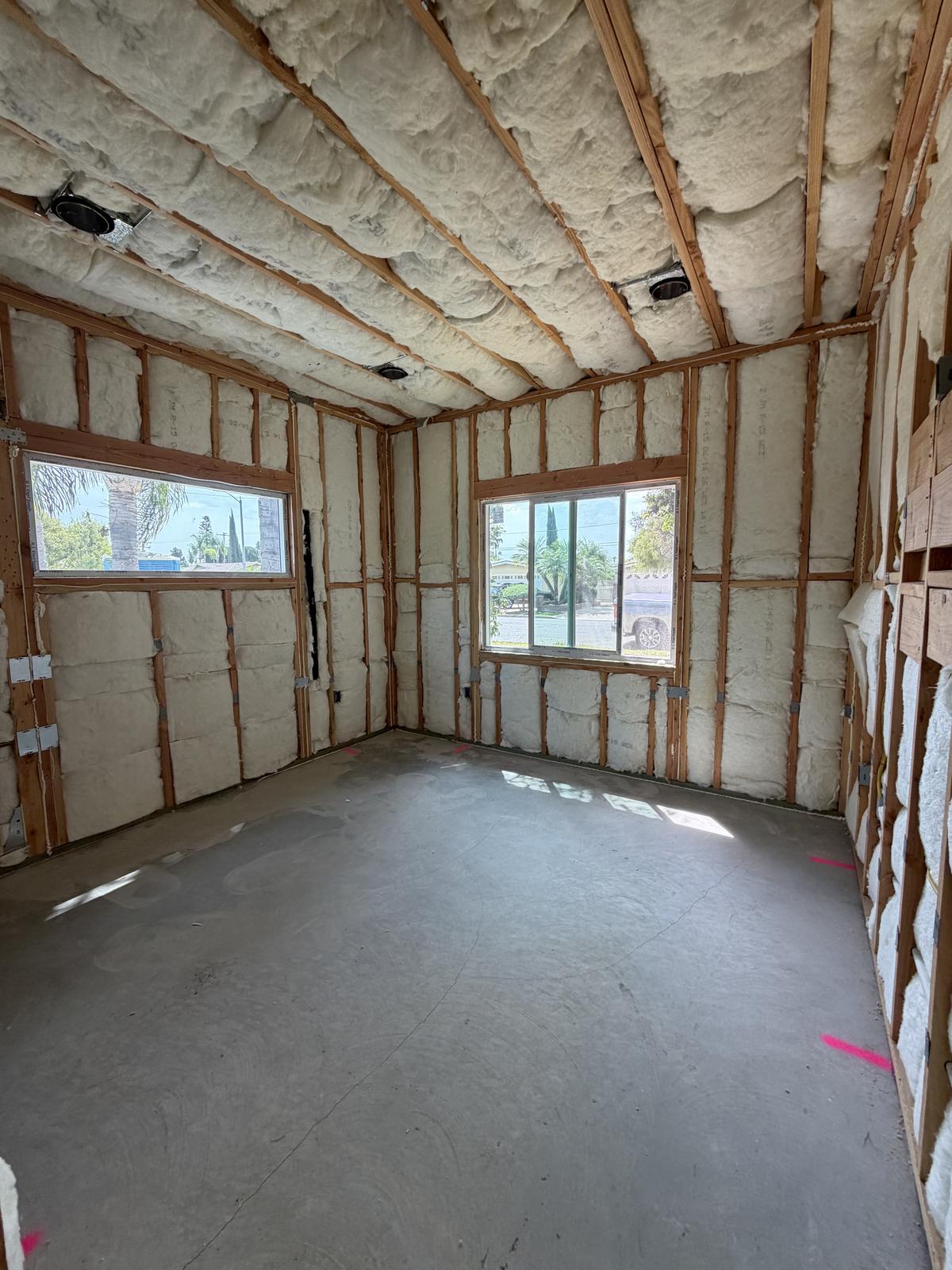Insulated ADU room with spray foam ceiling insulation and batt wall insulation before drywall