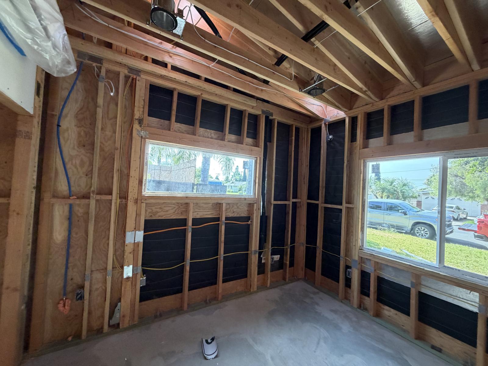 ADU room framing with black weather-resistive barrier visible in the wall cavities before insulation