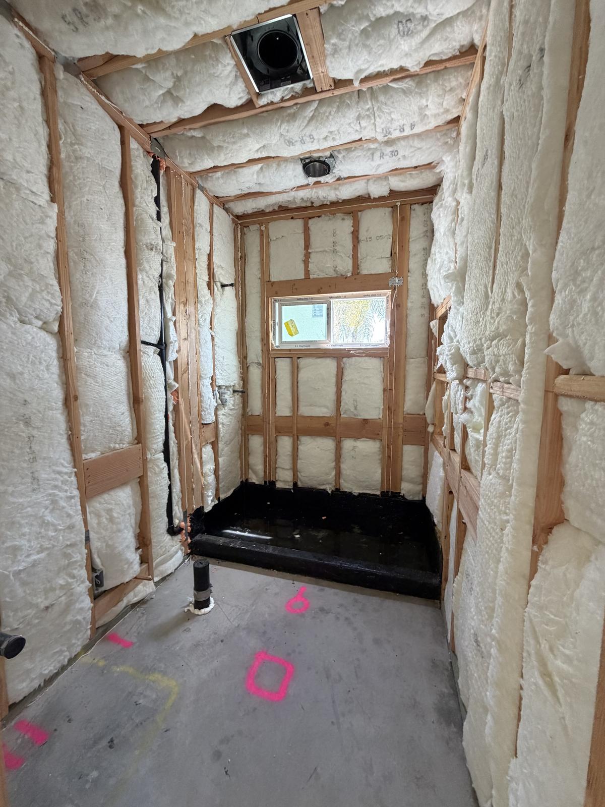 Insulated ADU bathroom framing with a waterproofed shower pan ready for tile