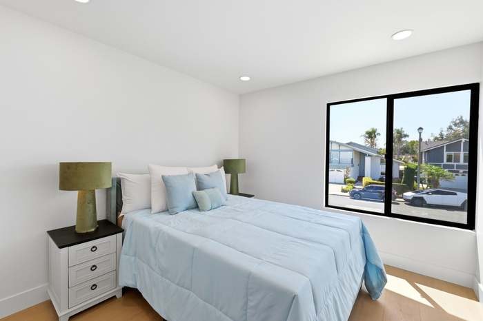 Bedroom with street-view window, blue bedding, and matching green table lamps