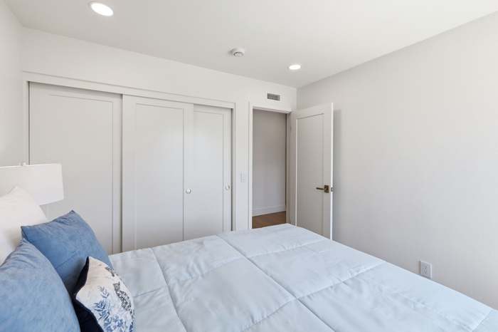 Bedroom with sliding closet doors, blue and white bedding, and a doorway to the hall