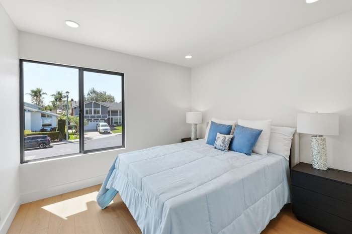 Bedroom with street-view window, blue bedding, and mismatched patterned table lamps