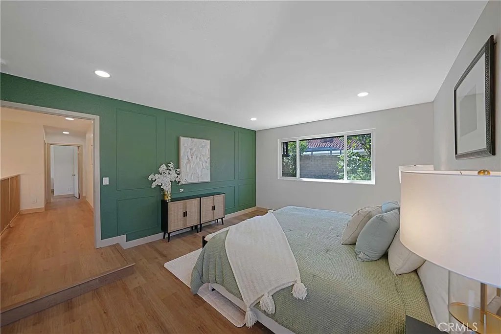 Primary bedroom with green paneled accent wall, built-in credenza, and view down the hallway