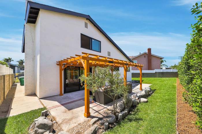Backyard patio with a custom wood pergola, boulder edging, and a new sod lawn