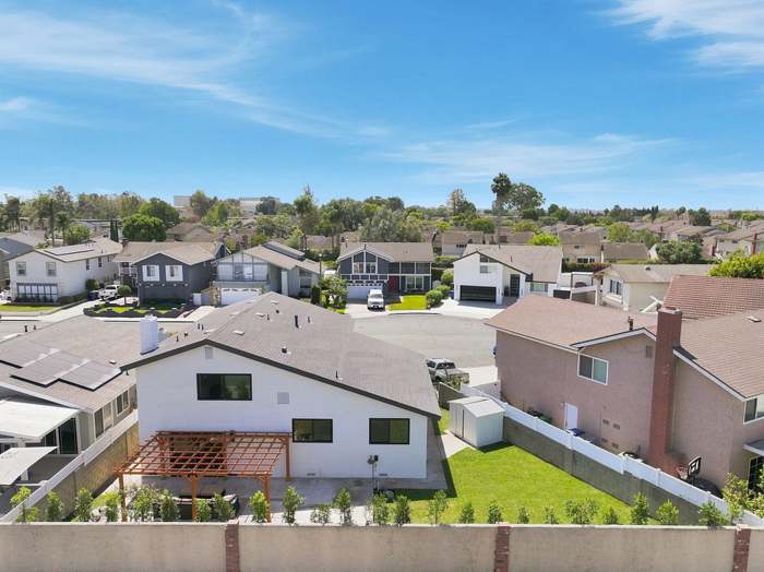 Aerial view of a backyard with a wood pergola, new lawn, and fresh landscaping along the fence line