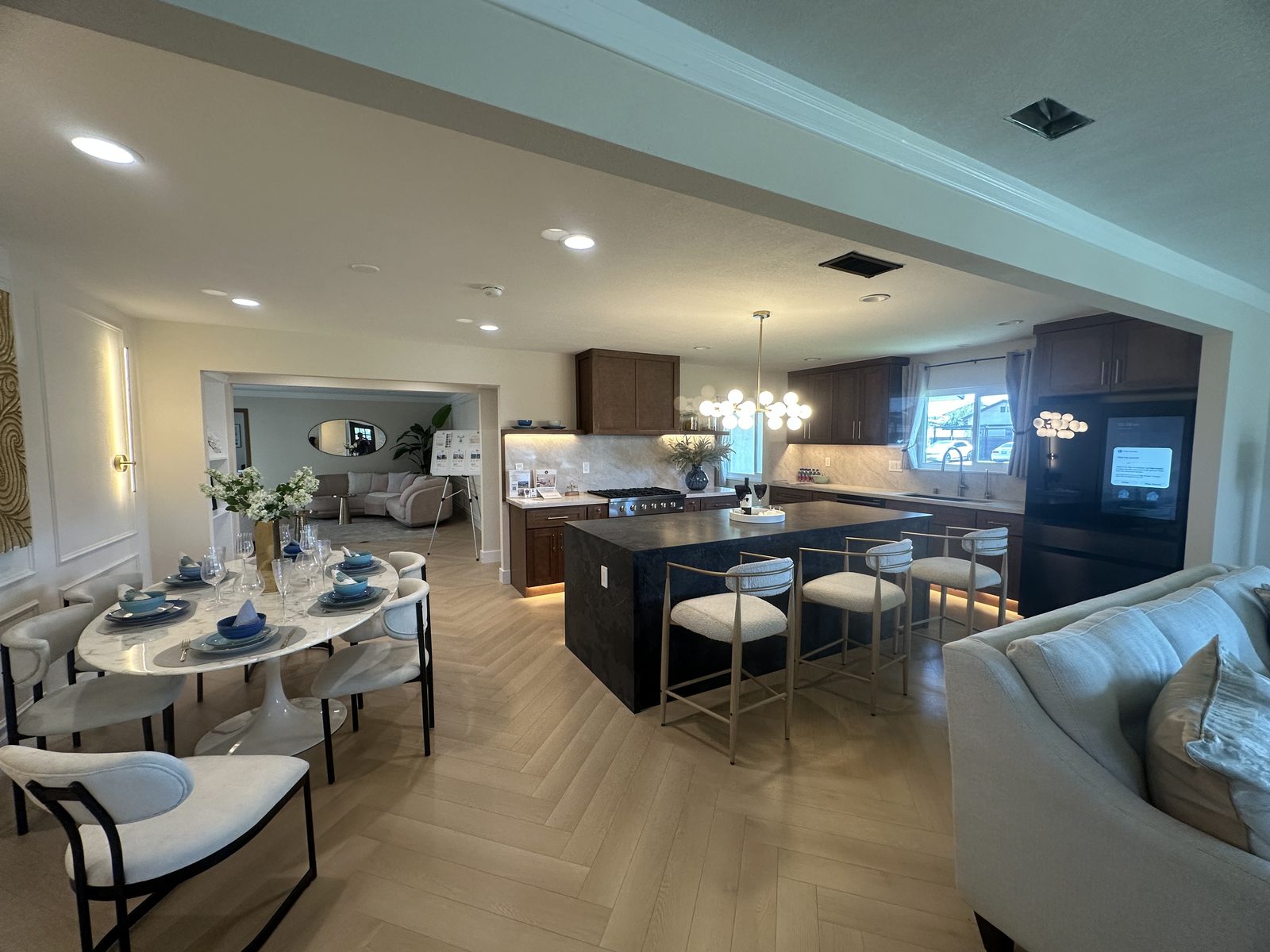 Open-concept kitchen with dark wood cabinetry, black waterfall island, and a gold globe chandelier