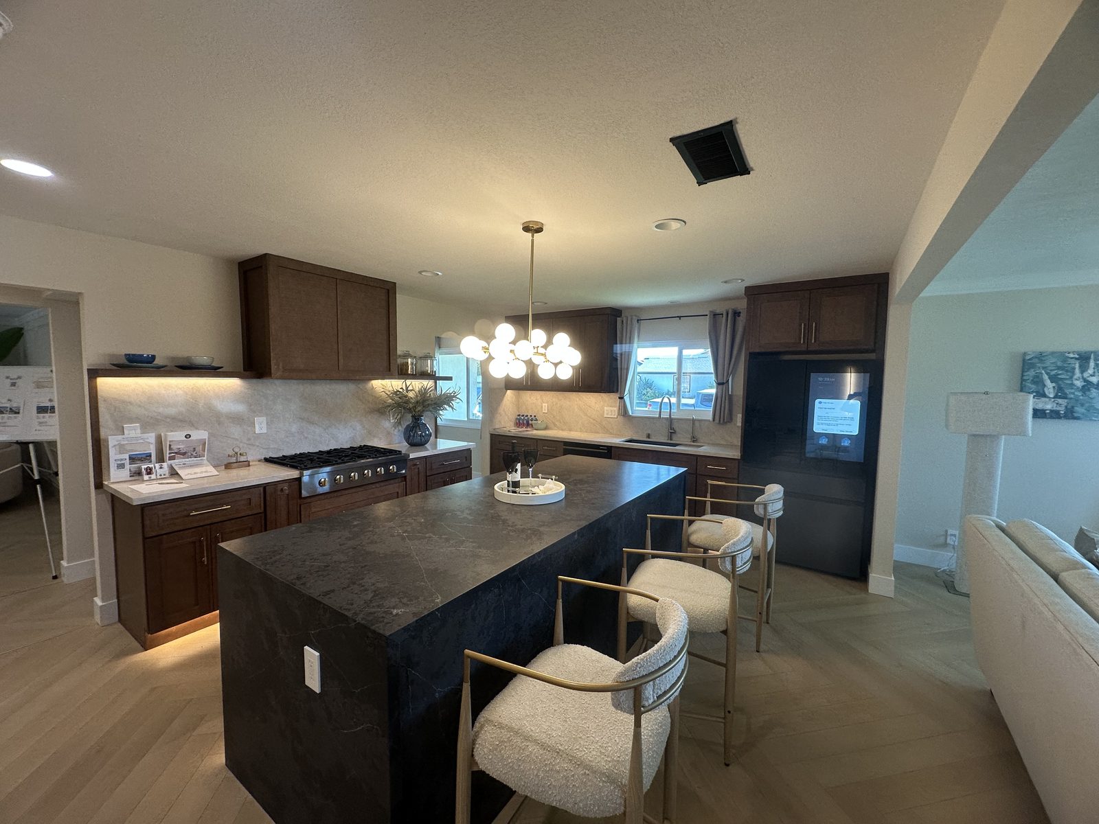 Dark wood kitchen with black stone waterfall island and stainless gas range