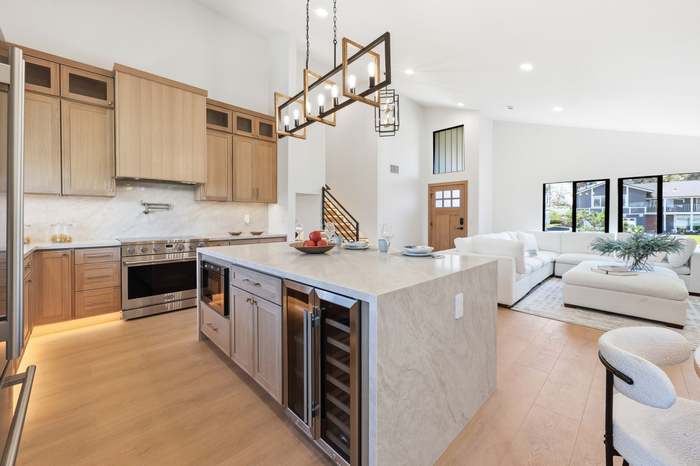 Open-concept kitchen with marble waterfall island, wine fridge, and view into the living room