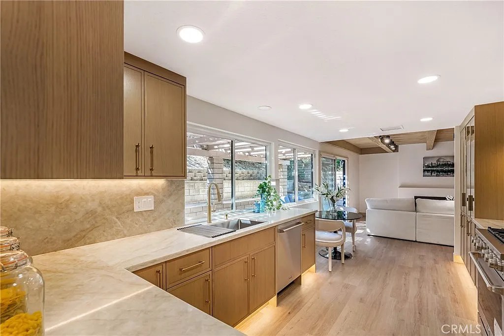 Kitchen counter with marble backsplash, gooseneck faucet, and view into an open living room