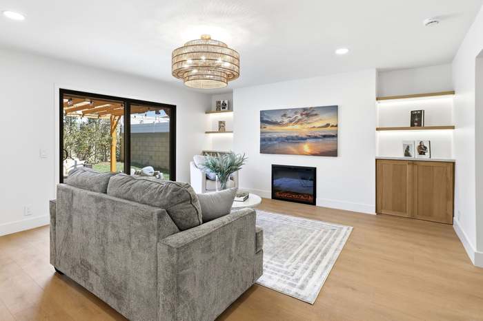 Living room with gray sofa, linear fireplace, built-in shelving, and sliding glass door to a covered patio