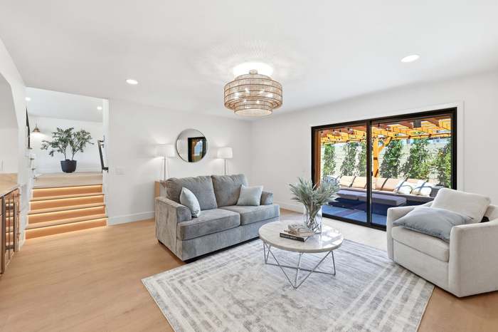 Living room with gray sofa, round coffee table, and sliding glass doors opening to a pool and pergola