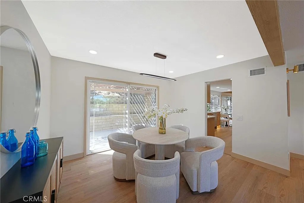 Dining nook with round table, upholstered chairs, and a sliding glass door out to a landscaped backyard