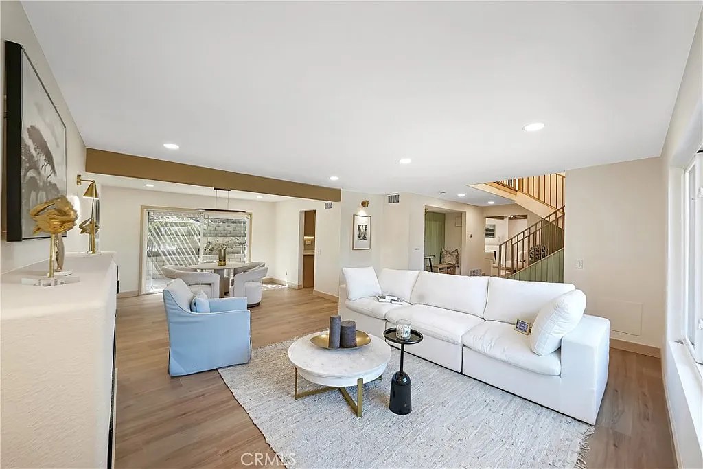 Open-concept living room with white sectional, round coffee table, and view into the dining area and staircase